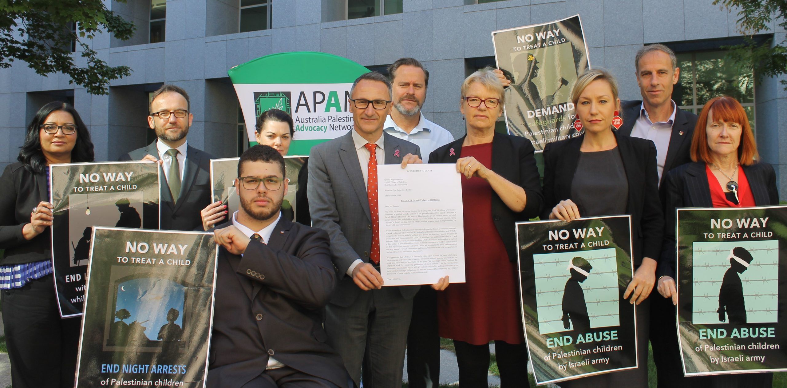 All Greens parliamentarians holding signs 'no way to treat a child'