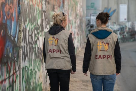 Phot of two peopel with EAPPI vests walking by the Israeli separation wall
