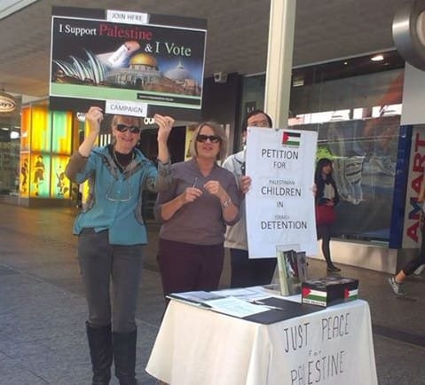 Picture of three activists in a shopping centre holding up signs