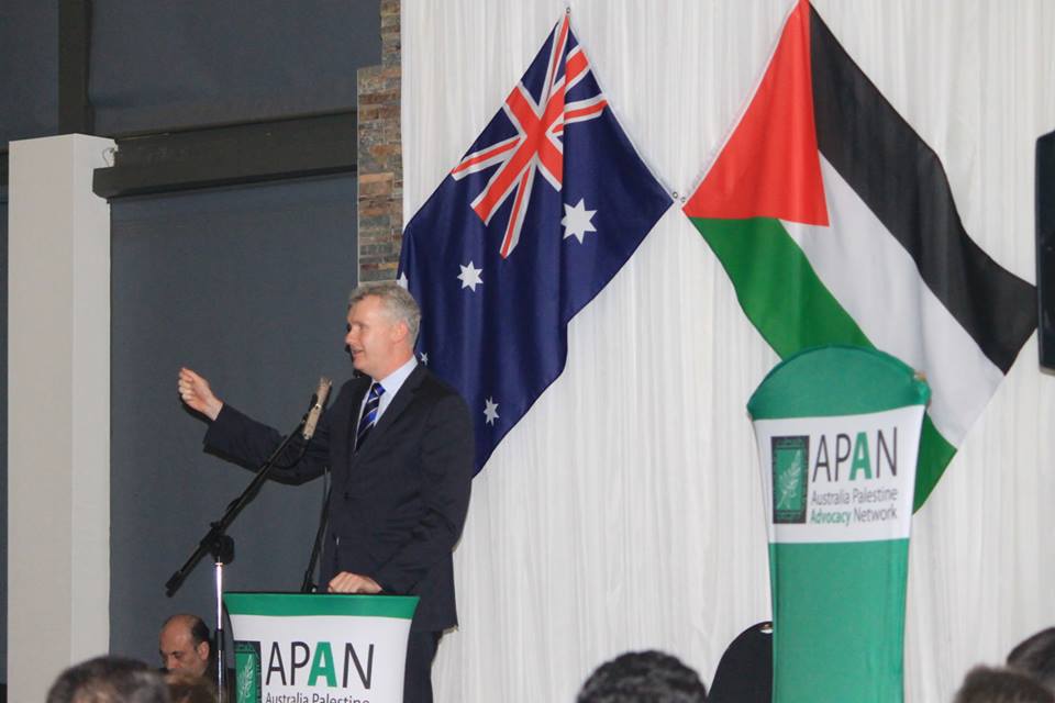 Photo of Tony Burke MP with APAN banners and Palestinian and Austrlaian flags in the background