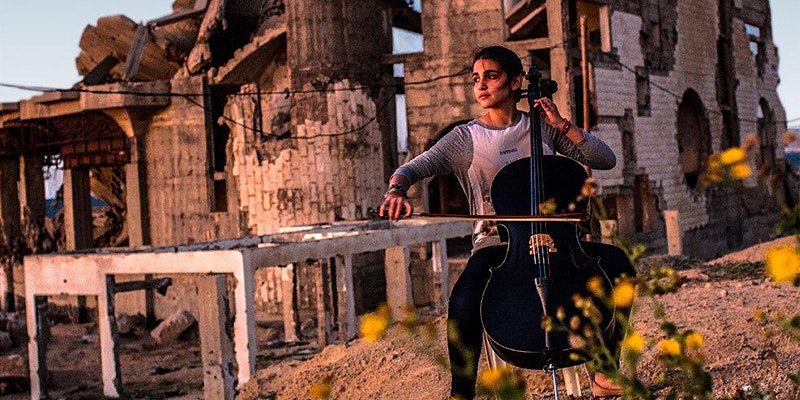 Woman playing double-bass in middle of rubble in Gaza