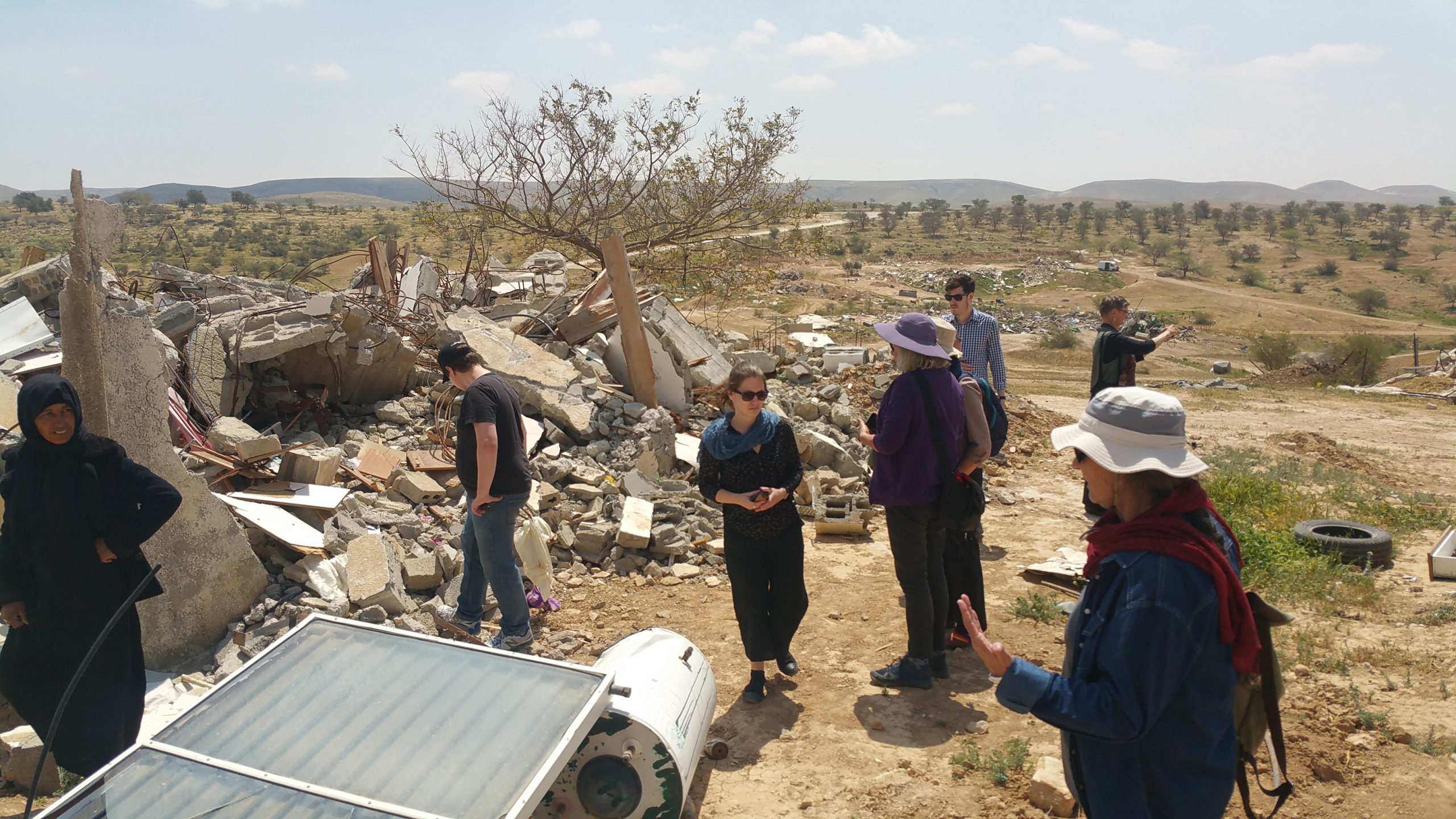 People walking around demolished village