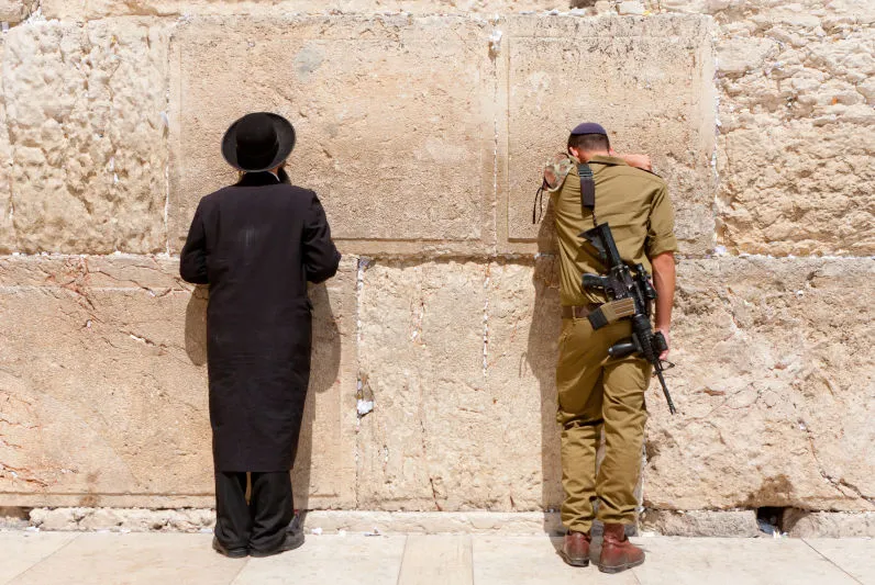 Photo of an Israeli soldier and an Orthodox Jew praying at the wailing wall