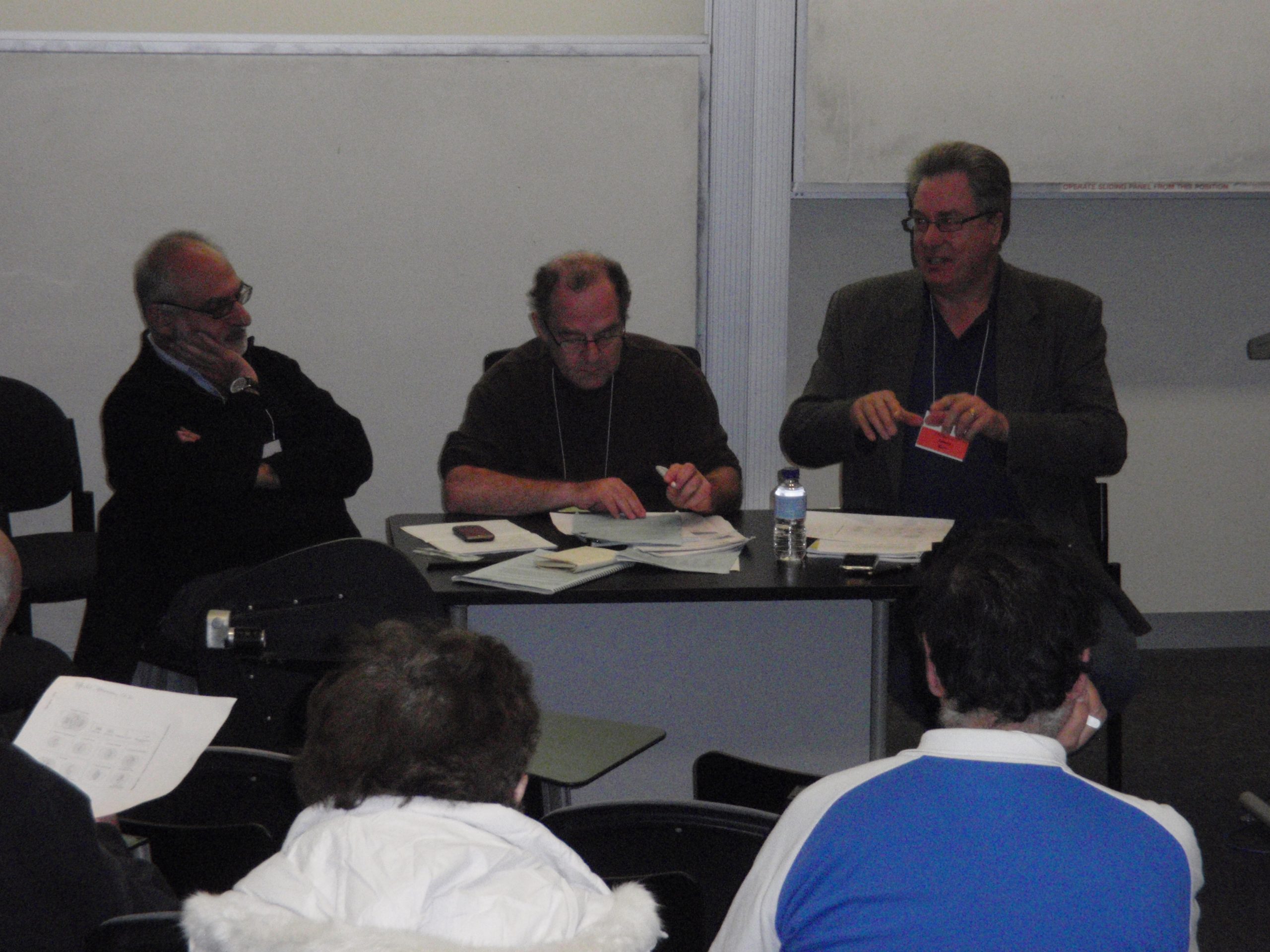 Three men at a table talking to an audience