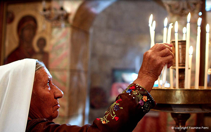 The Stones Cry Out Image of Palestinian Christian Woman lighting candles in a church