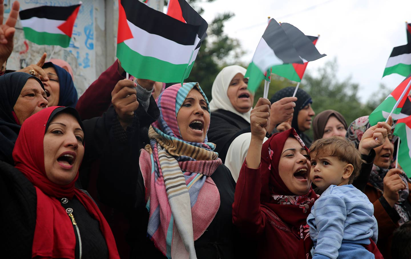 Women (some holding children) waving Palestinian flags in protest