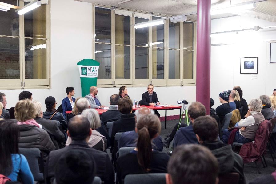 A room of people with four people sitting at a table at the front