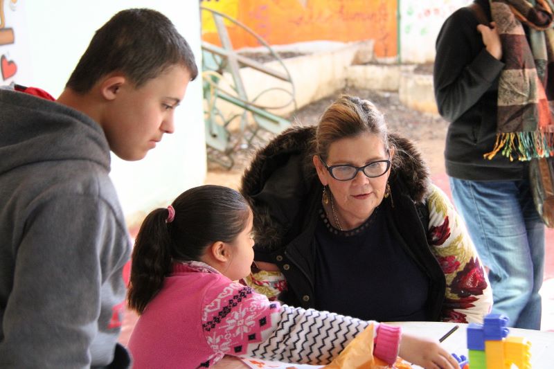Woman listening to two children with Down Syndrome sharing their work